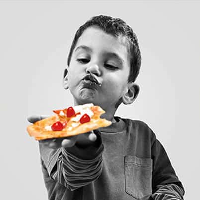 Boy Eating Pizza with PEPPADEW® Sweet Piquanté Peppers